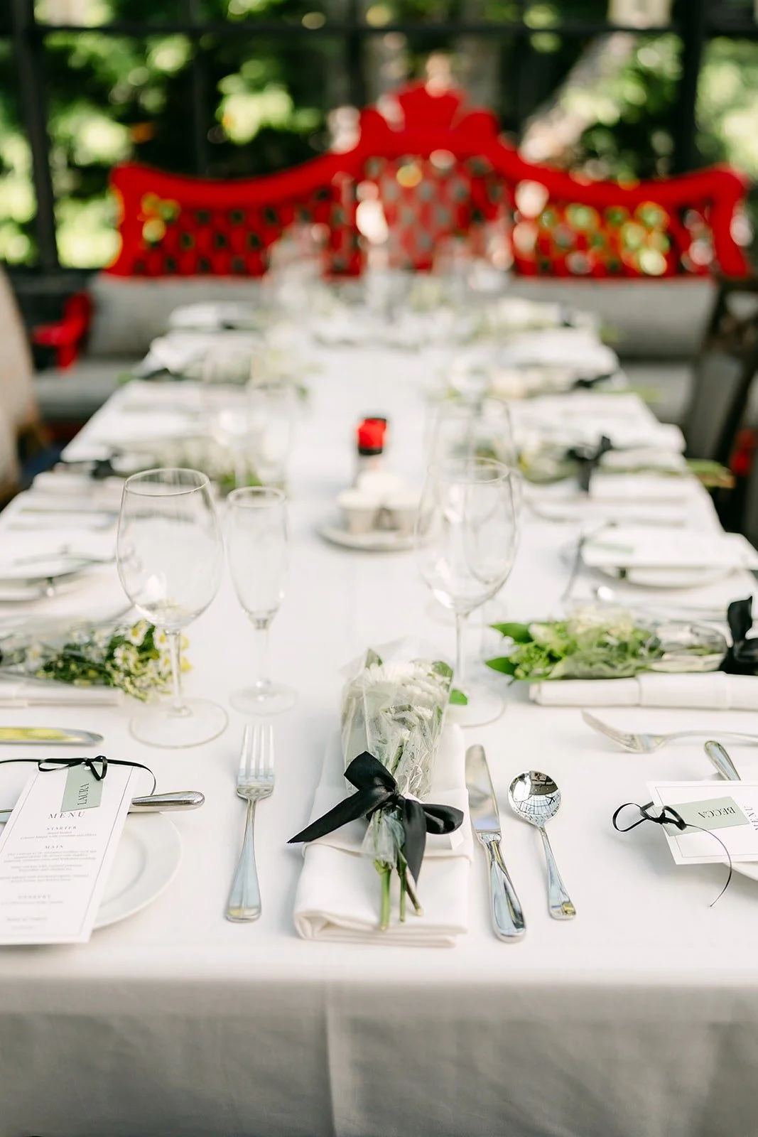 Long reception tables with white linens and black ribbon tied napkins