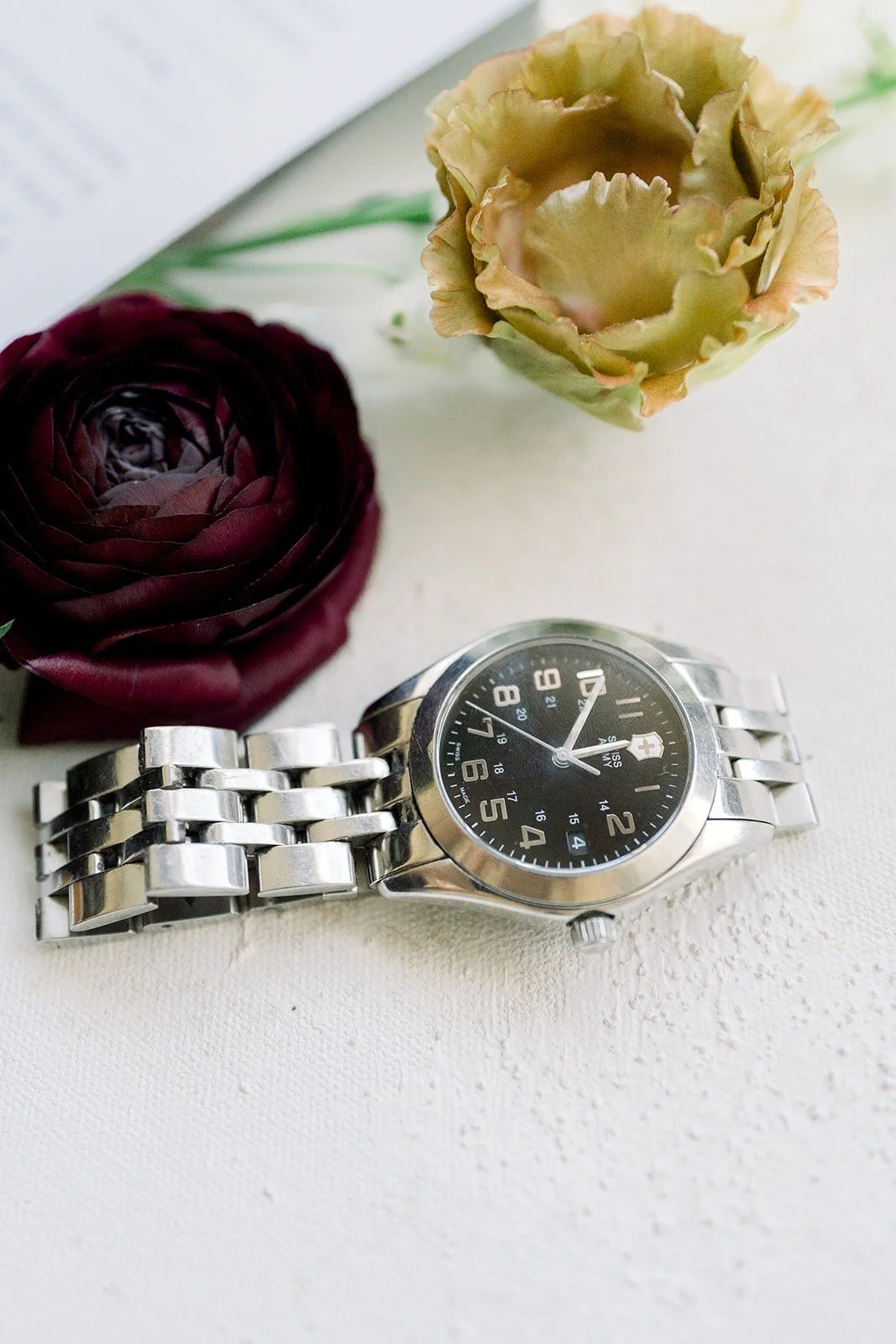 Mikey's silver watch beside burgundy and blush flowers