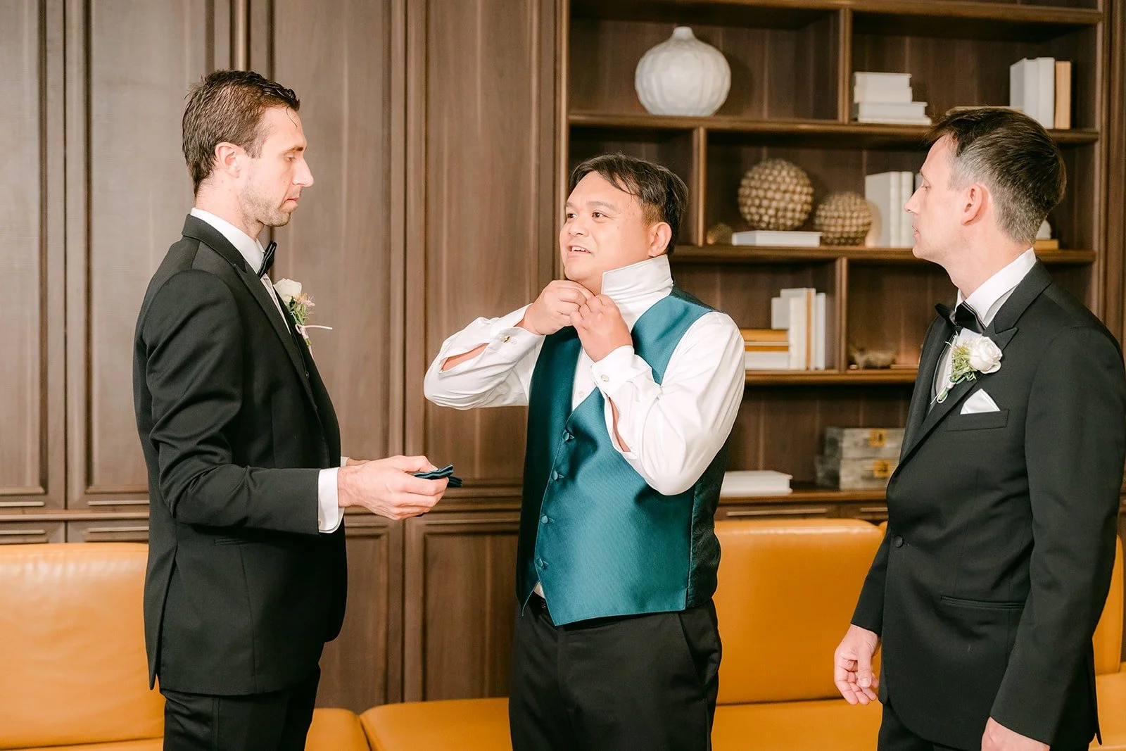 Groomsmen helping James button his teal vest at the Sheraton Los Angeles San Gabriel