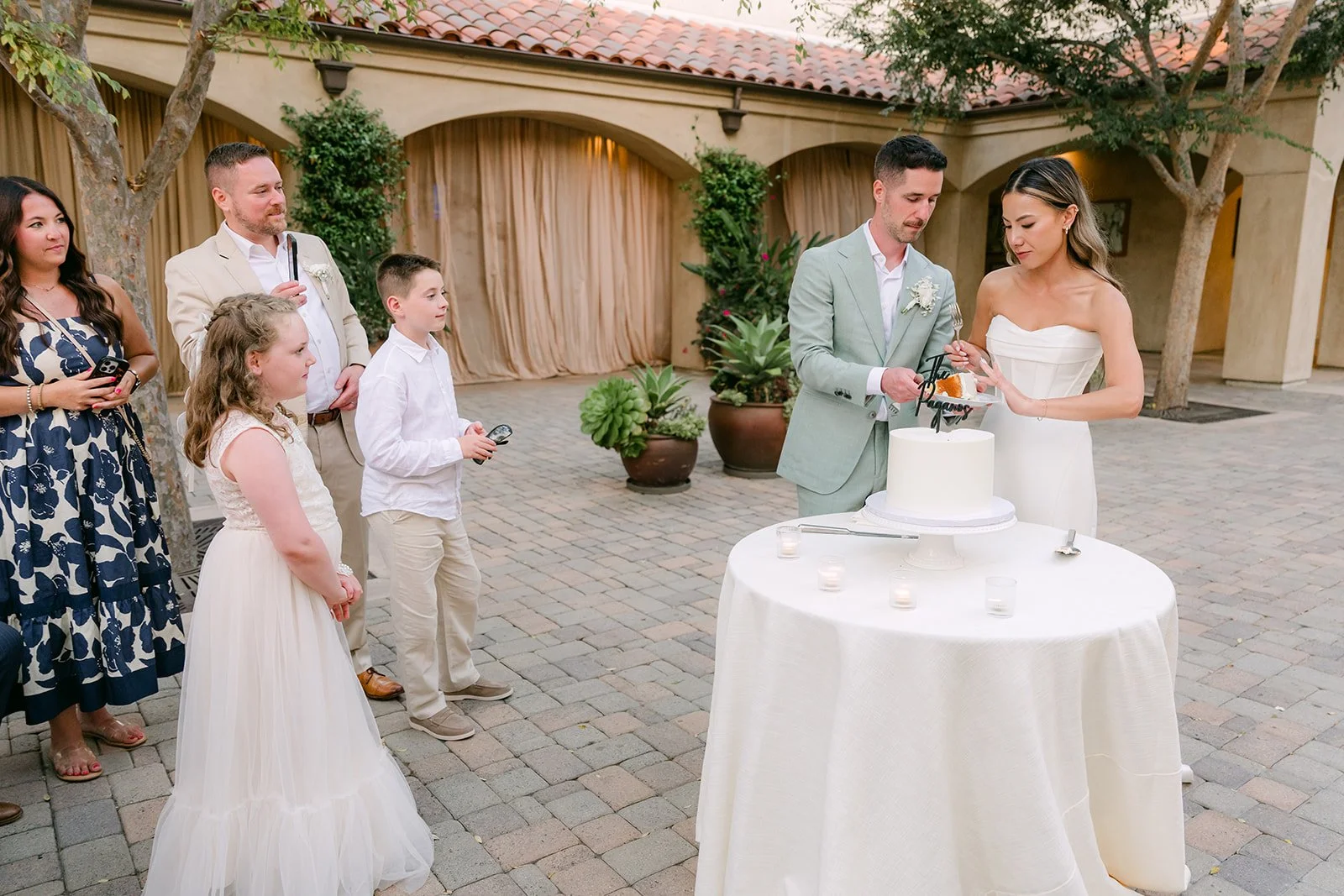 Couple cutting their wedding cake while guests look on