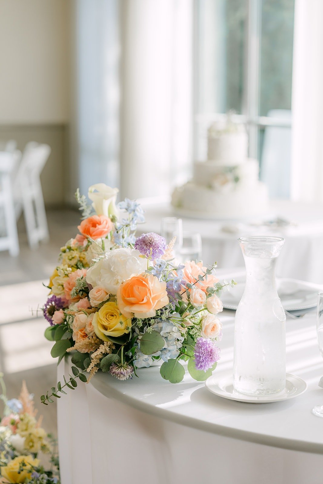 A pastel centerpiece with the wedding cake behind it