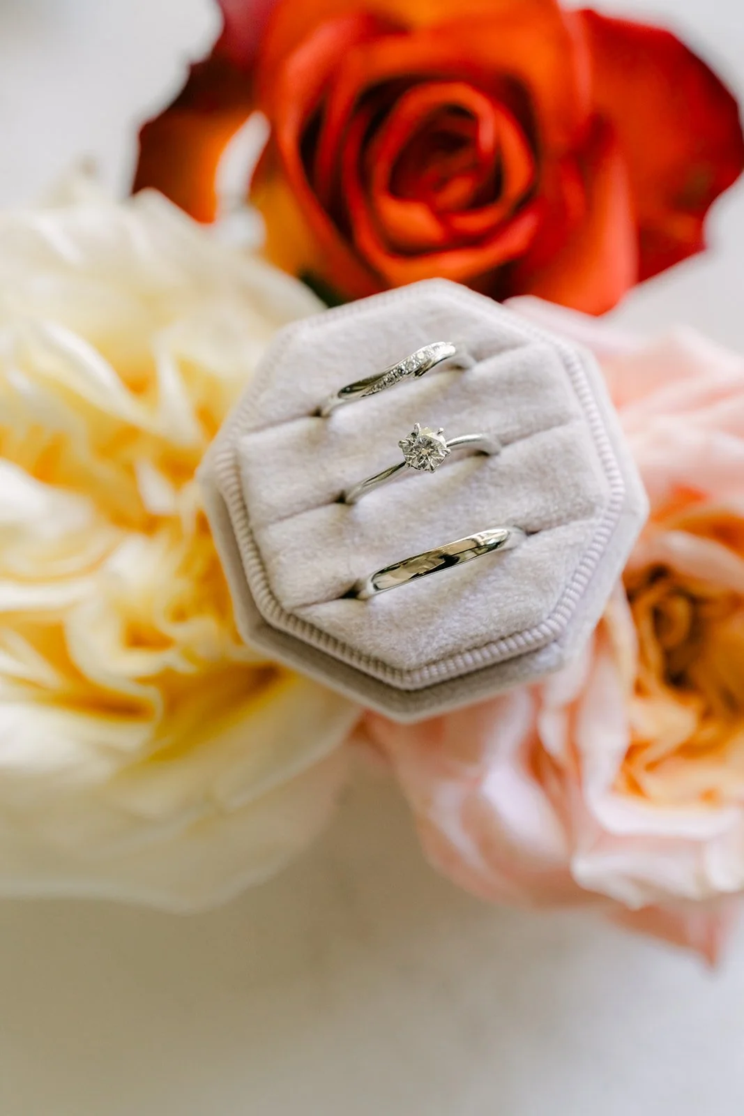 Engagement ring in a hexagon ring box surrounded by peach and orange roses