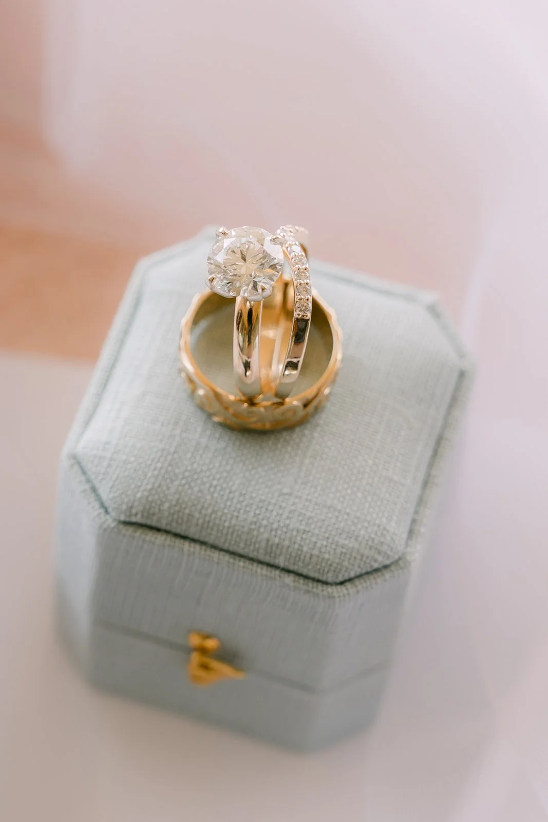 The wedding rings stacked on a sage velvet ring box