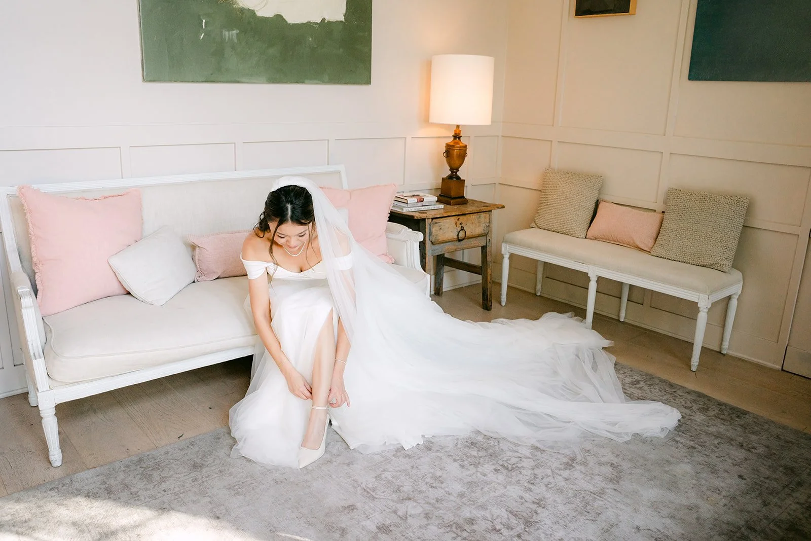 Jadee in her gown on the sofa in the bright bridal suite at The Harper