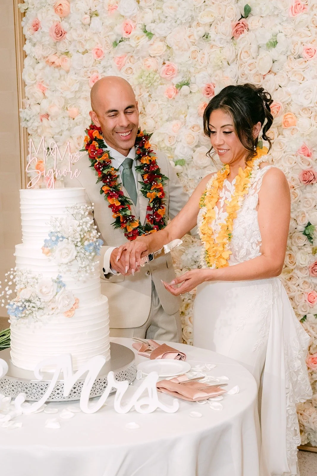 Francesca and Daniel smile as they cut the cake beside a Mrs sign