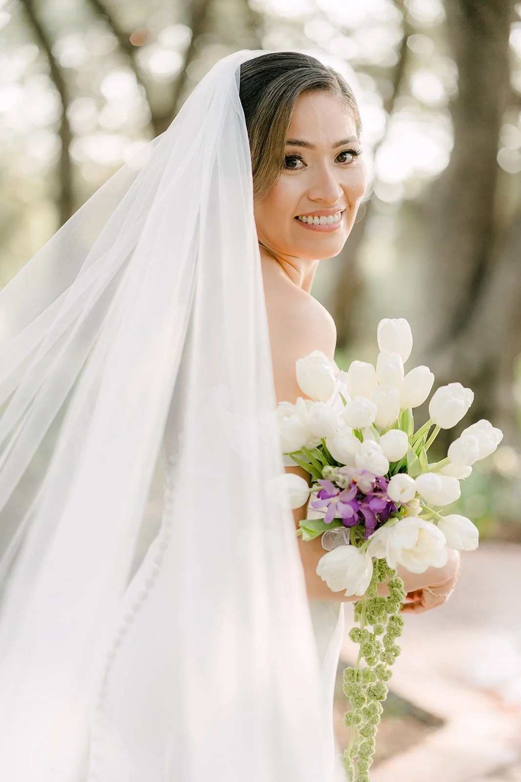Mariana holding her white calla lily bouquet with her veil framing her face