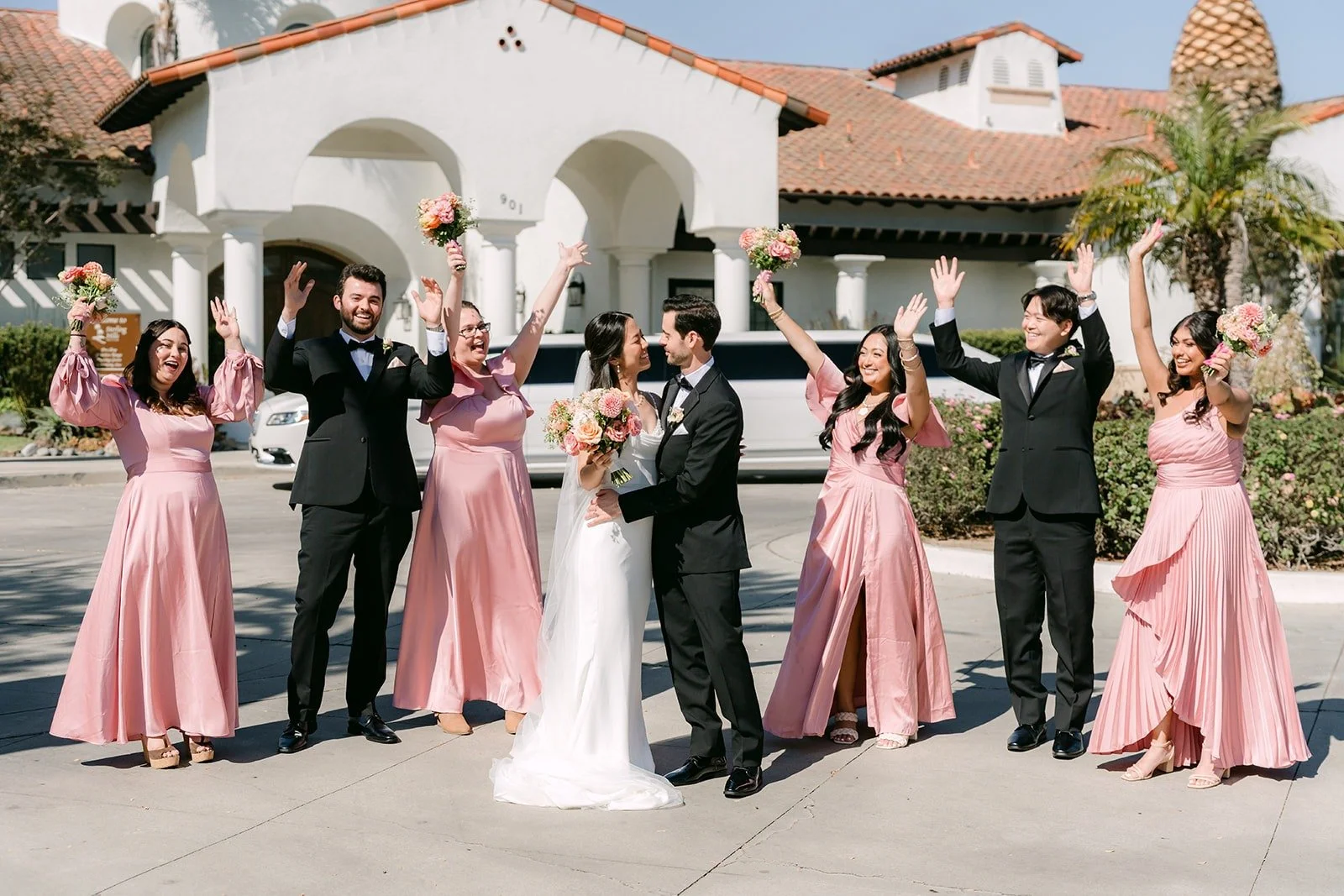 The wedding party throwing their arms up in celebration around Stephanie and Kevin