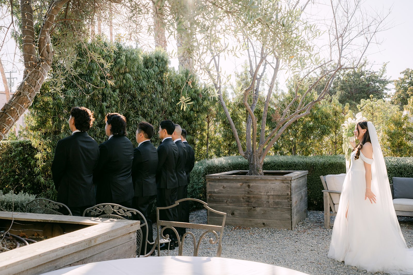 Wide view of the garden first look with the bridal party watching, photographed by One and Only Production