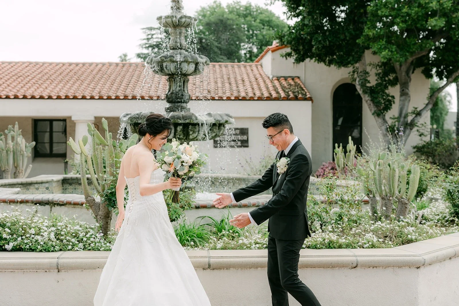 Eric reaching out to Eunice during their first look by the fountain at San Gabriel Mission