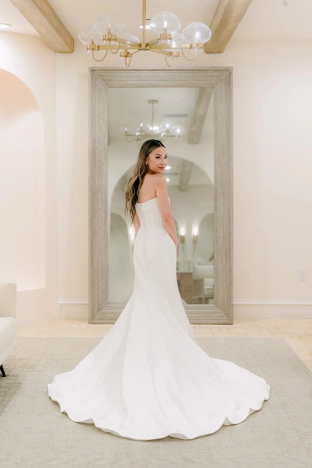 Back view of the bride's mermaid gown and long train in the bridal suite mirror