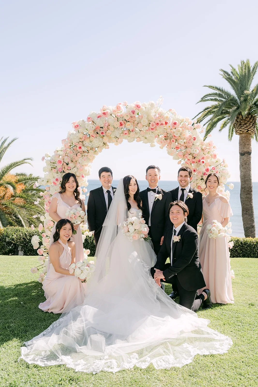 Full wedding party under the floral arch at Bel-Air Bay Club