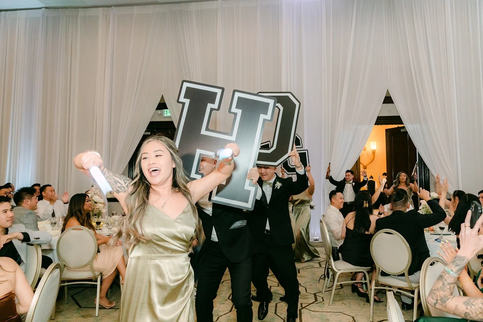 The wedding party dancing in holding giant letters