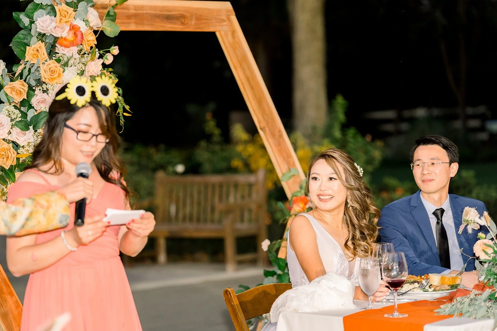 A bridesmaid giving a toast beside Ariel and Alex