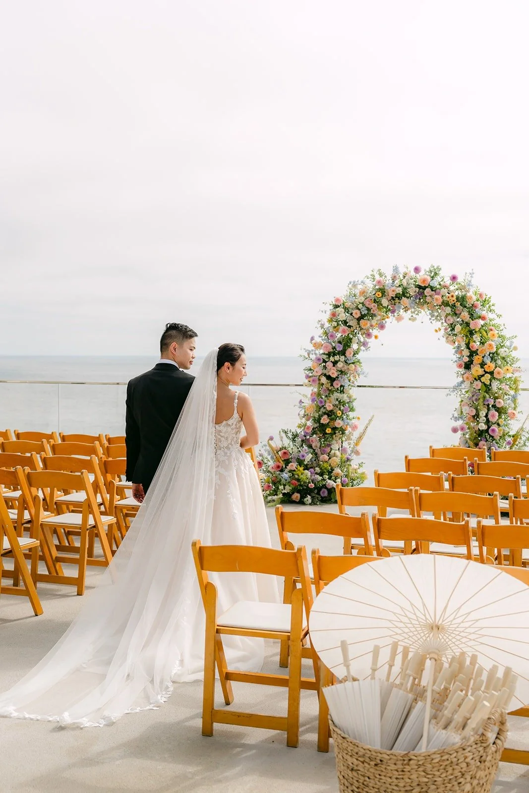 Kylie and Mario walking toward the floral arch past the rows of wooden chairs