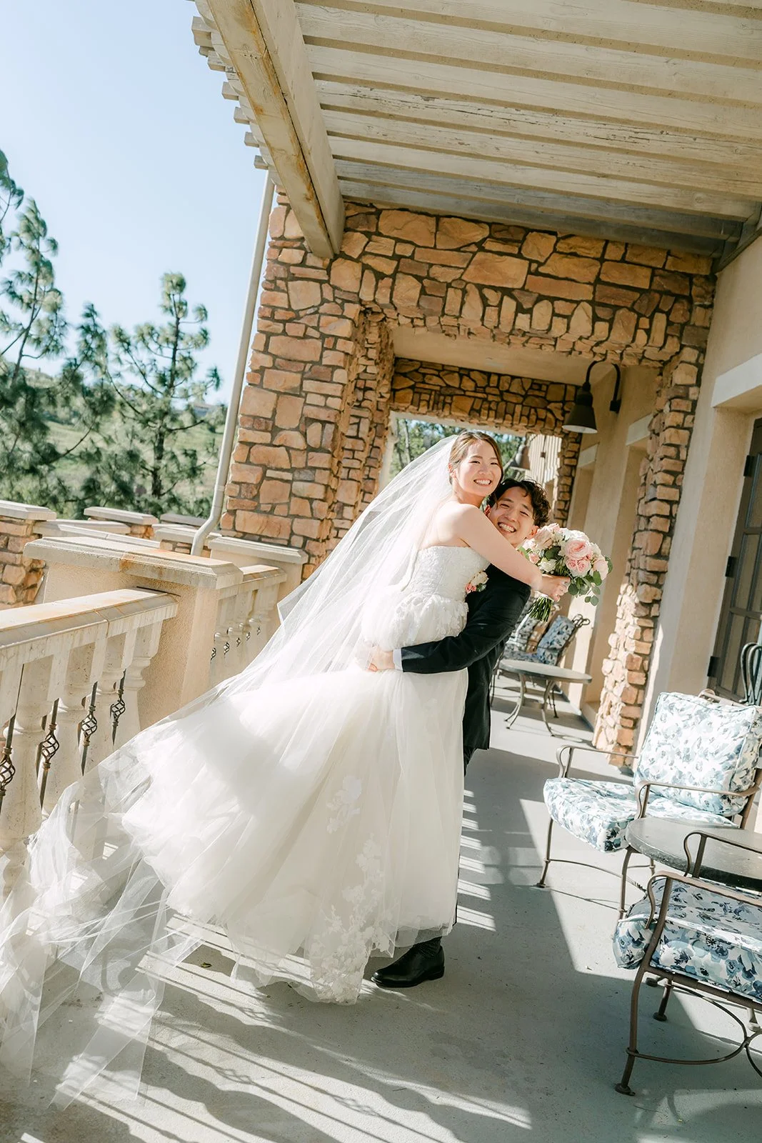 Groom lifting the bride on the sunlit terrace