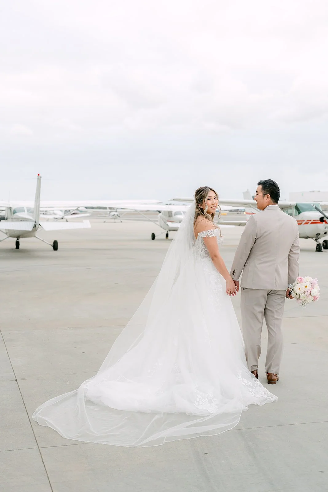 Raine and Ricky walking hand in hand past parked planes