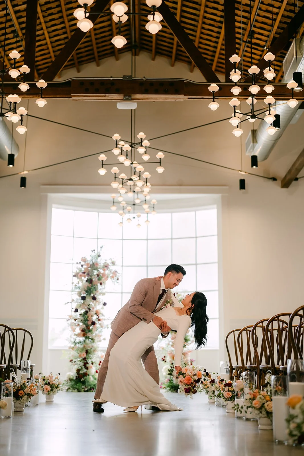 Michael kissing Denise at the end of the aisle, wide view of the ballroom.