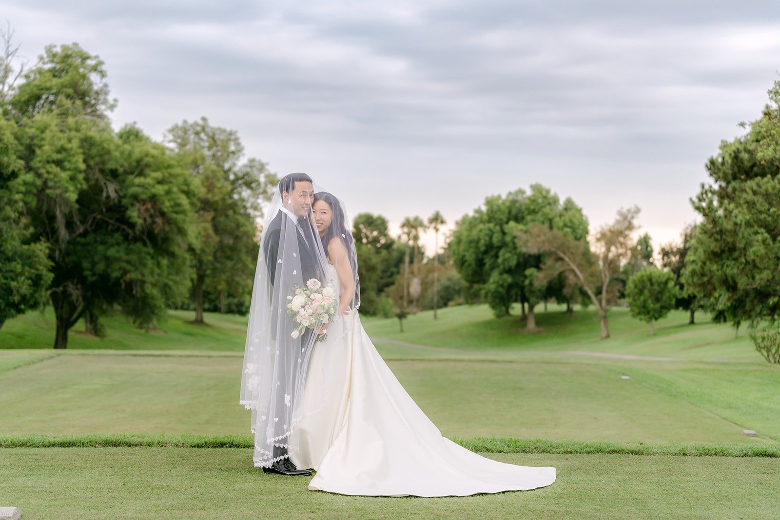 Kristine and William standing on the fairway under a wide sky, photographed by One and Only Production