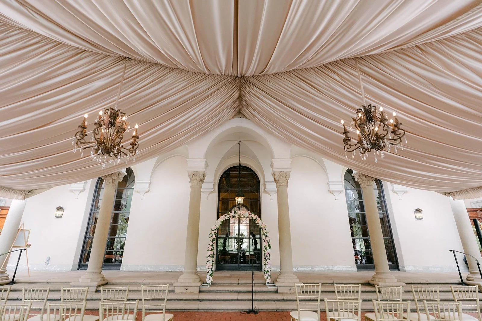 Draped fabric ceilings and crystal chandeliers over the ceremony seating