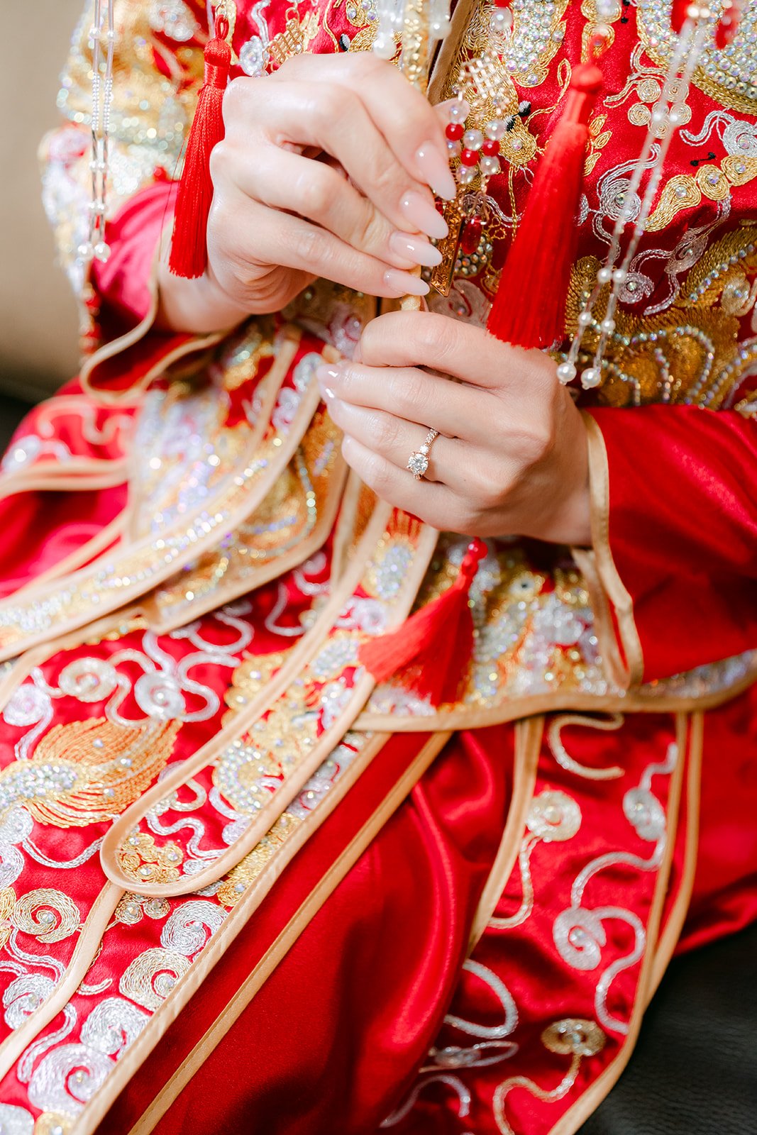 The bride's hands resting on the gold phoenix embroidery of her qun kwa.