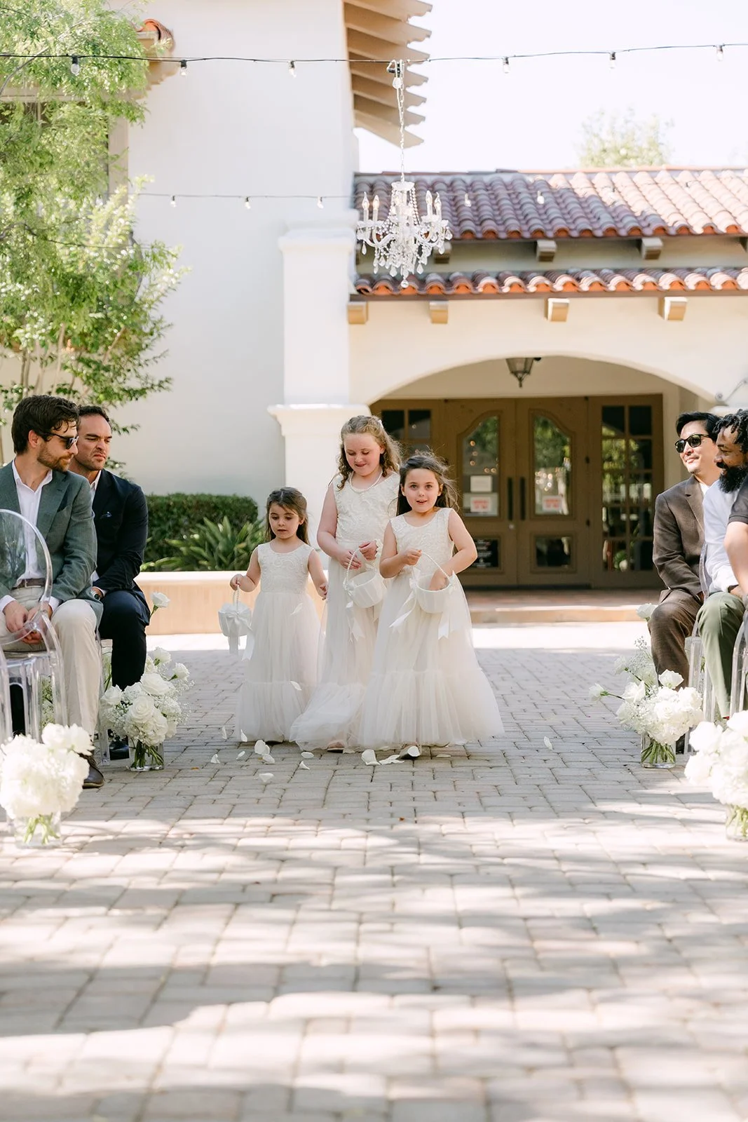 Flower girls walking down the courtyard aisle