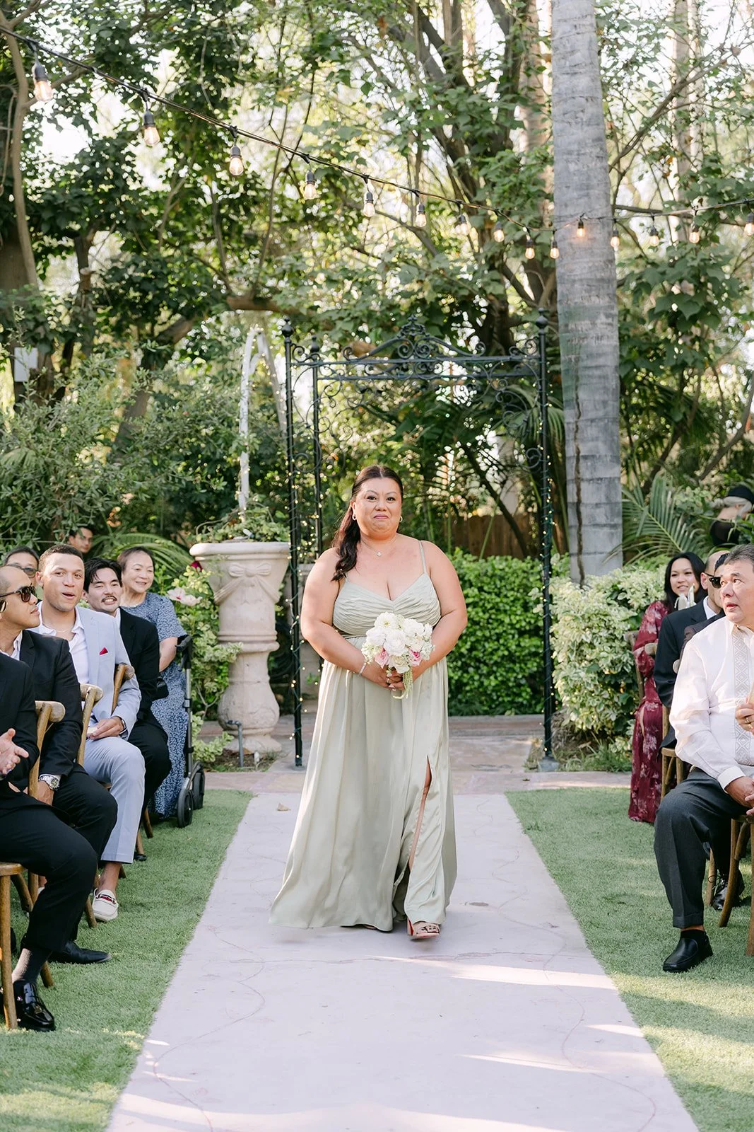A bridesmaid in pistachio green walking down the aisle at Eden Gardens.