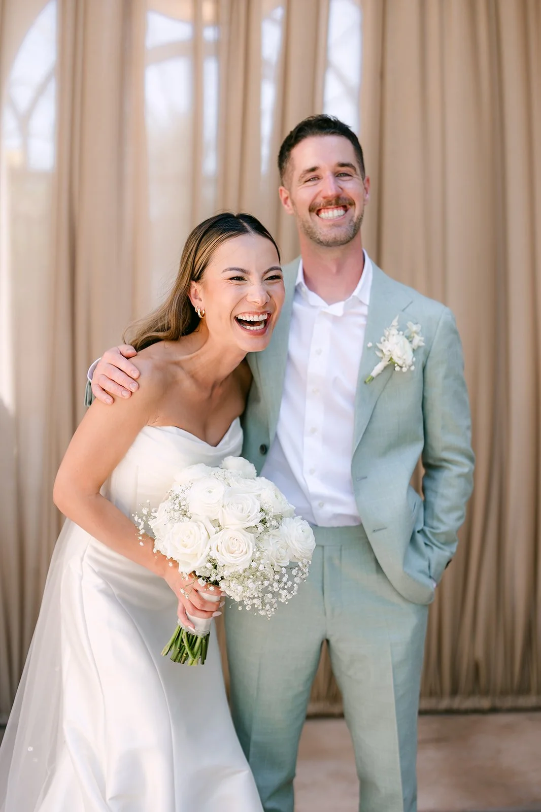 Bride and groom laughing together with her white bouquet