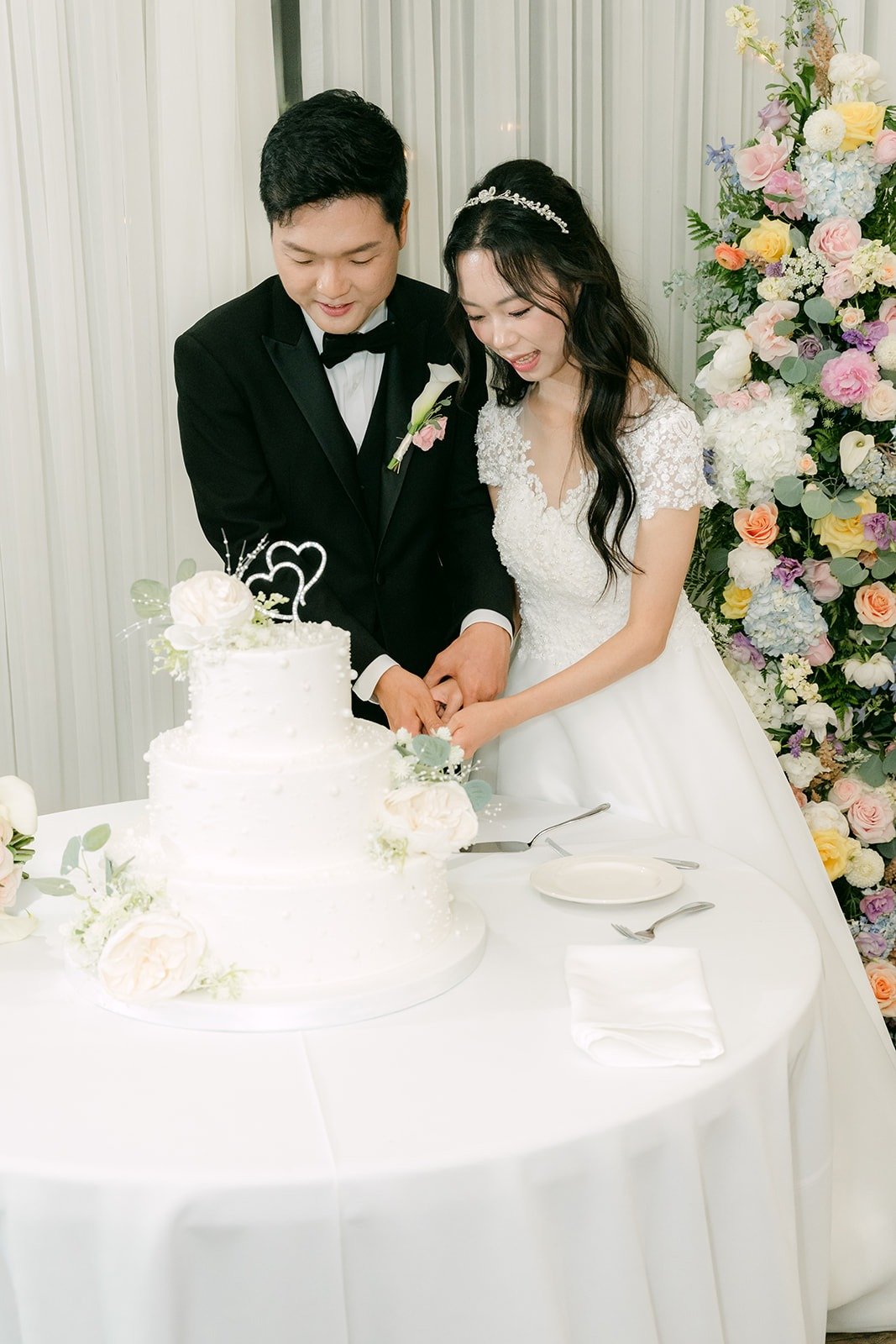 Jeannie and Eunsang smiling as they cut the cake