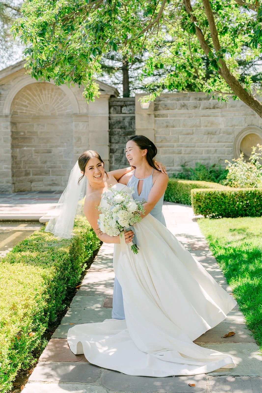 A bridesmaid fixing Brianna's veil in the garden