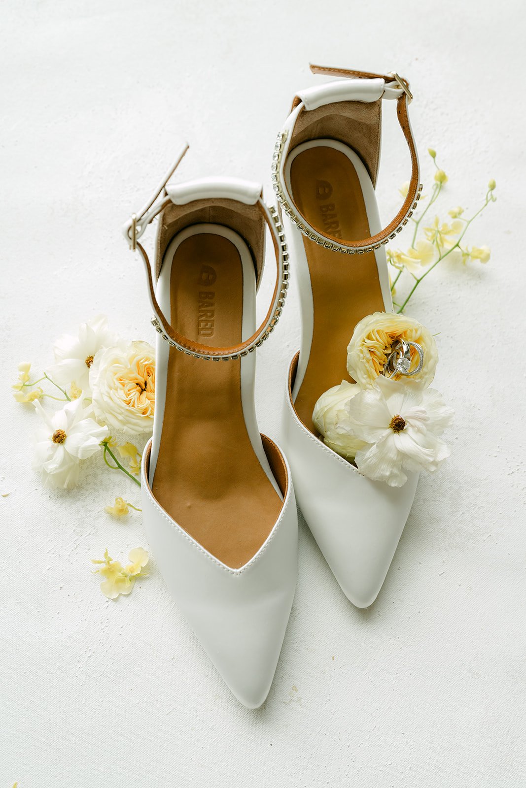 Jenny's white bridal heels with pearl straps beside yellow florals.