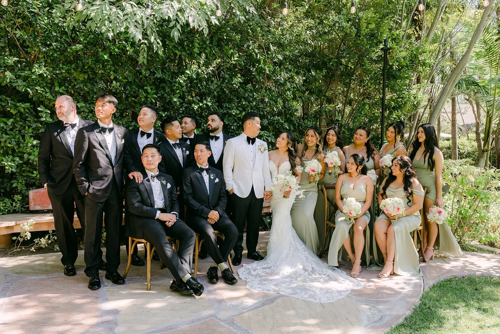 Nicole and Caryl's wedding party smiling together in the garden.
