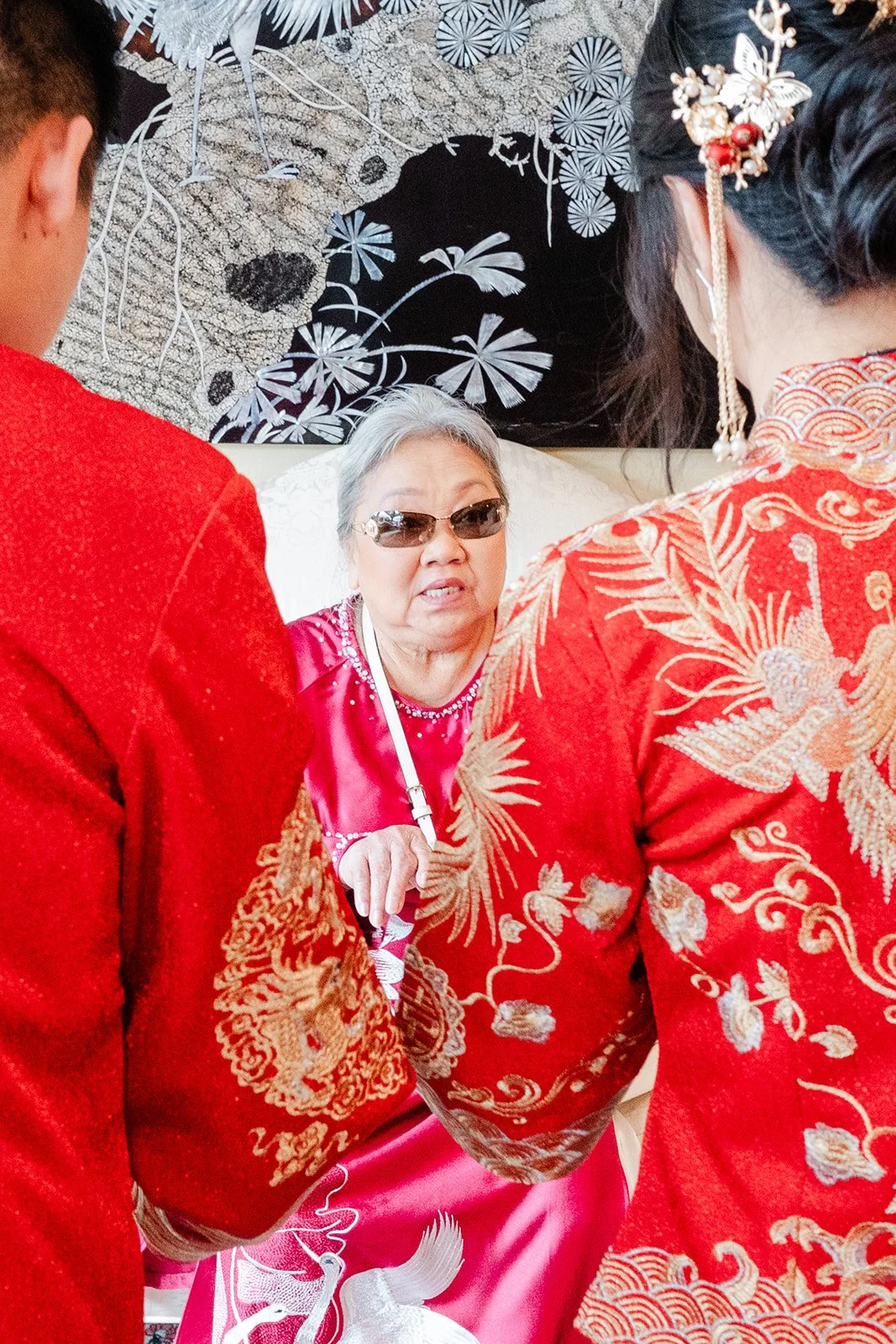 An elder in sunglasses smiling beside the bride.