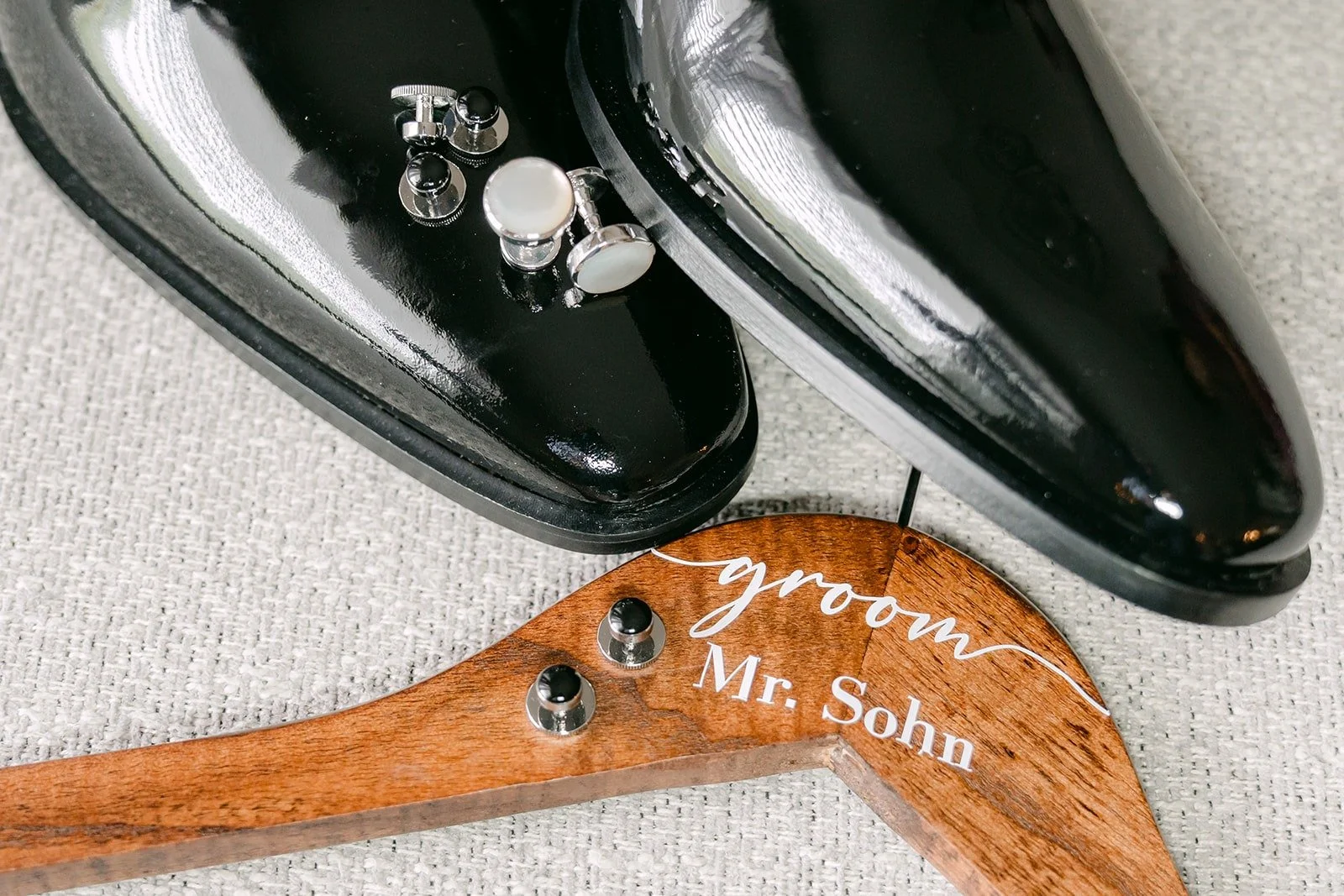Cufflinks set on William's shoes next to the engraved groom hanger, photographed by One and Only Production