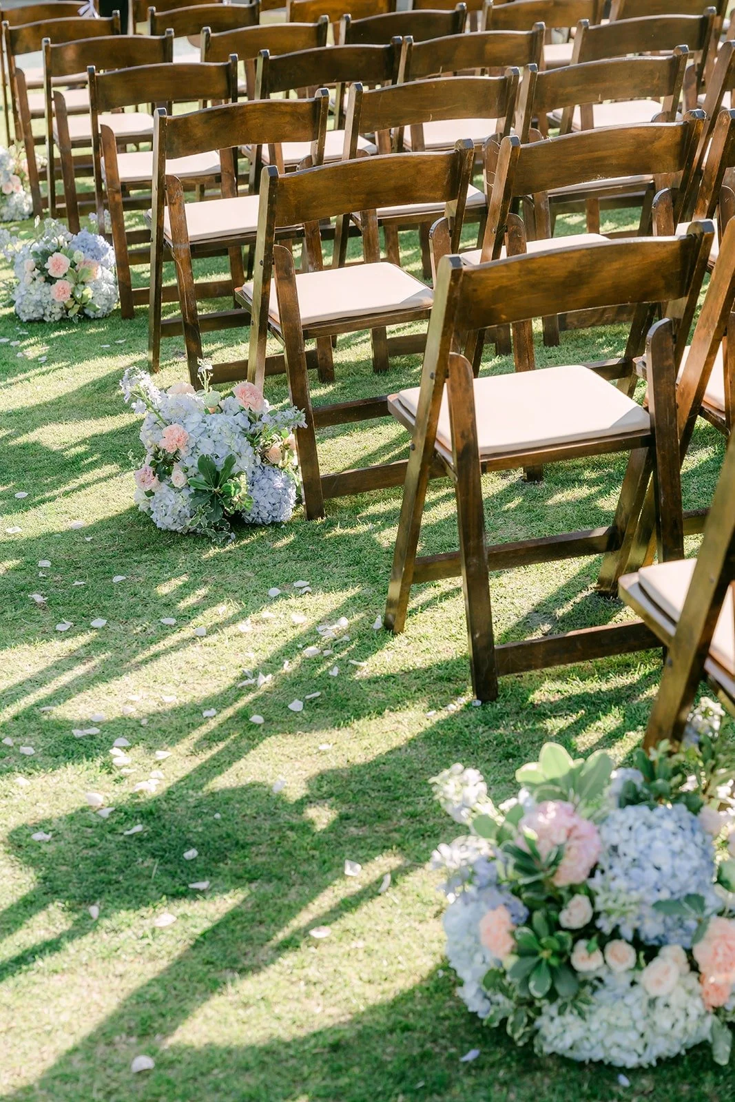 Blue hydrangea arrangements lining the aisle of wooden chairs