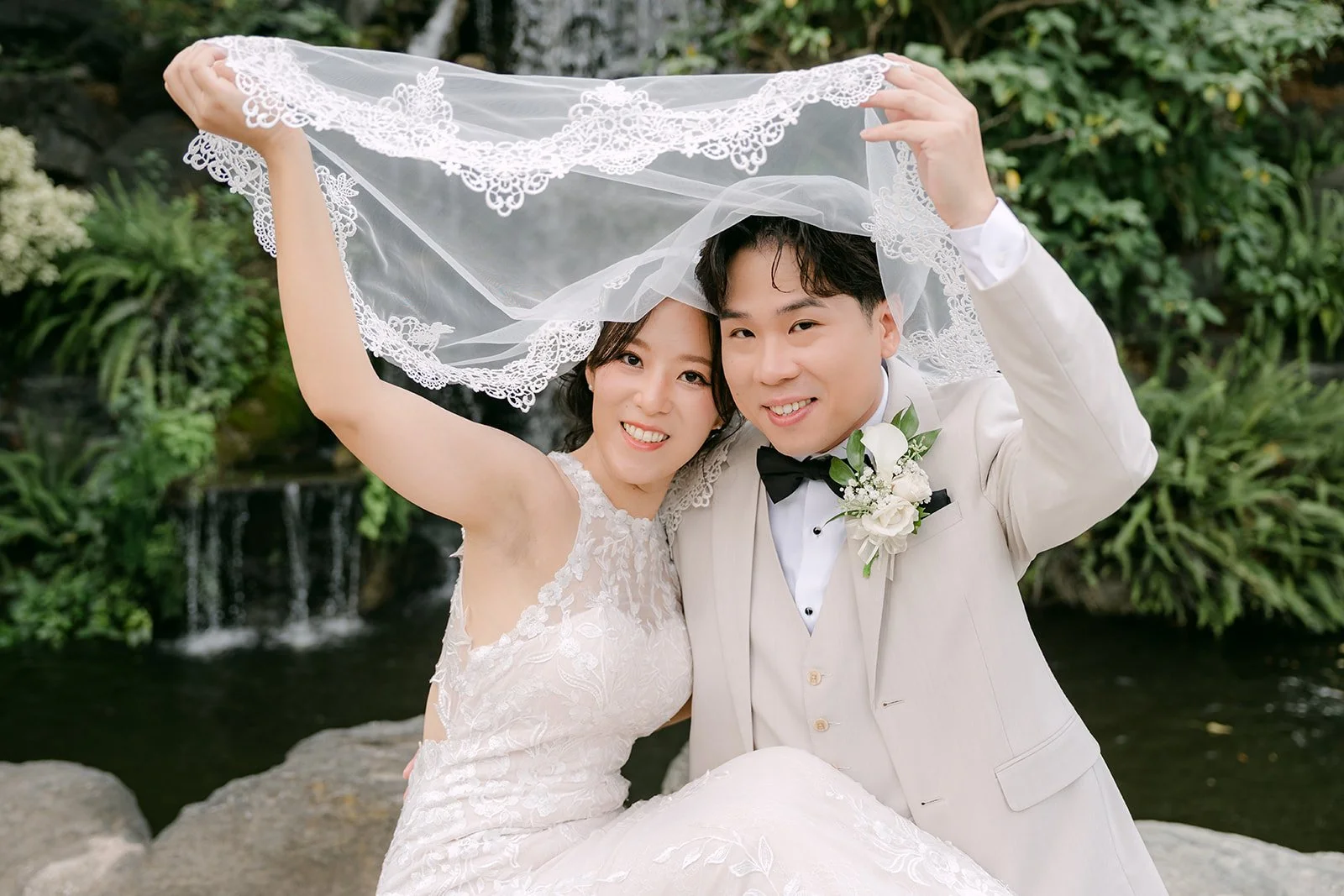 Elaine holding her veil over the two of them by the waterfall.
