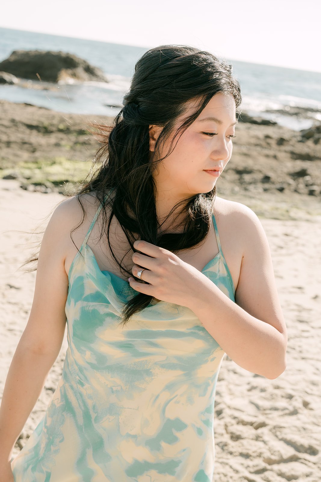 Constance brushing her hair back by the ocean.