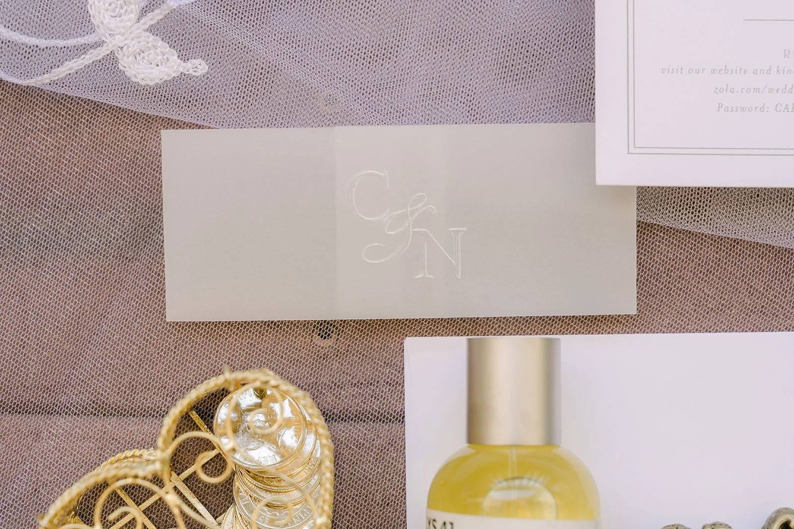 Pale green invitation suite with a gold ring box and perfume bottle on Nicole's draped veil.