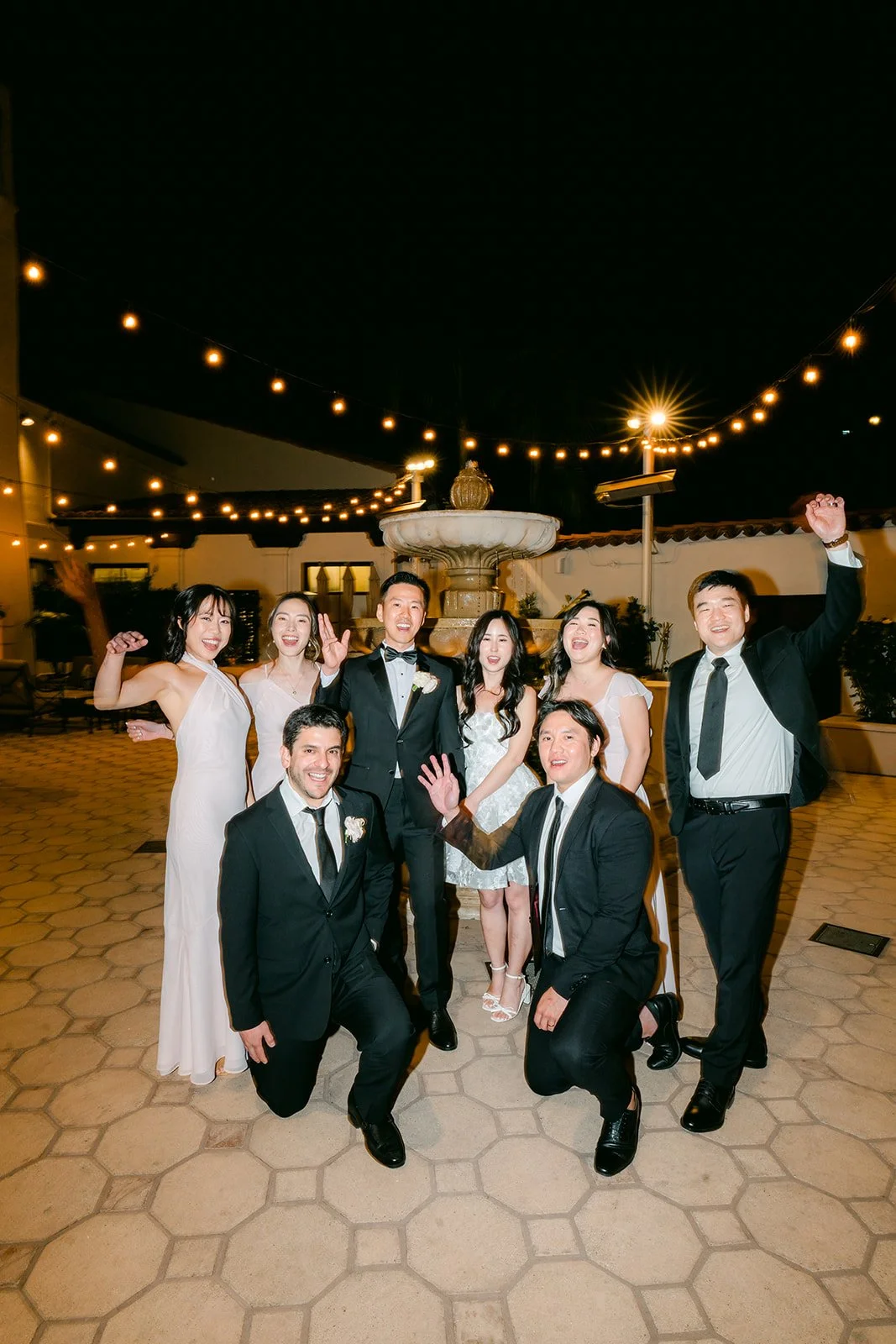 Wedding party posing playfully in the courtyard at night