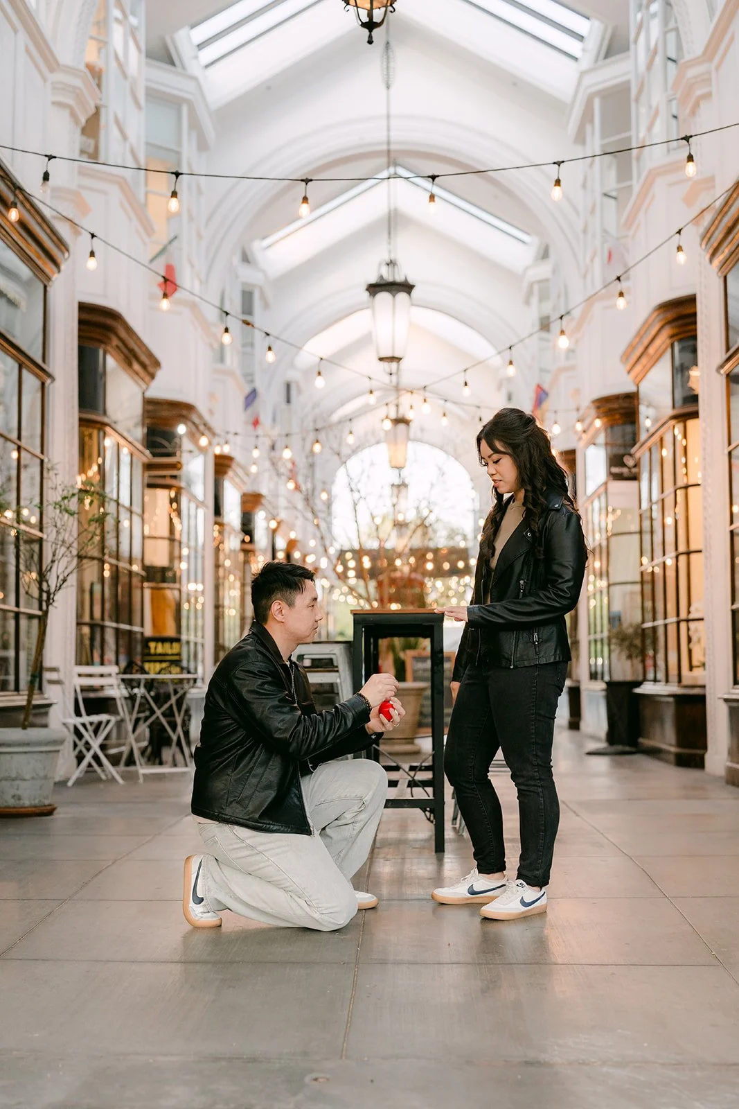 James crouches in front of Emily in the middle of the arcade.