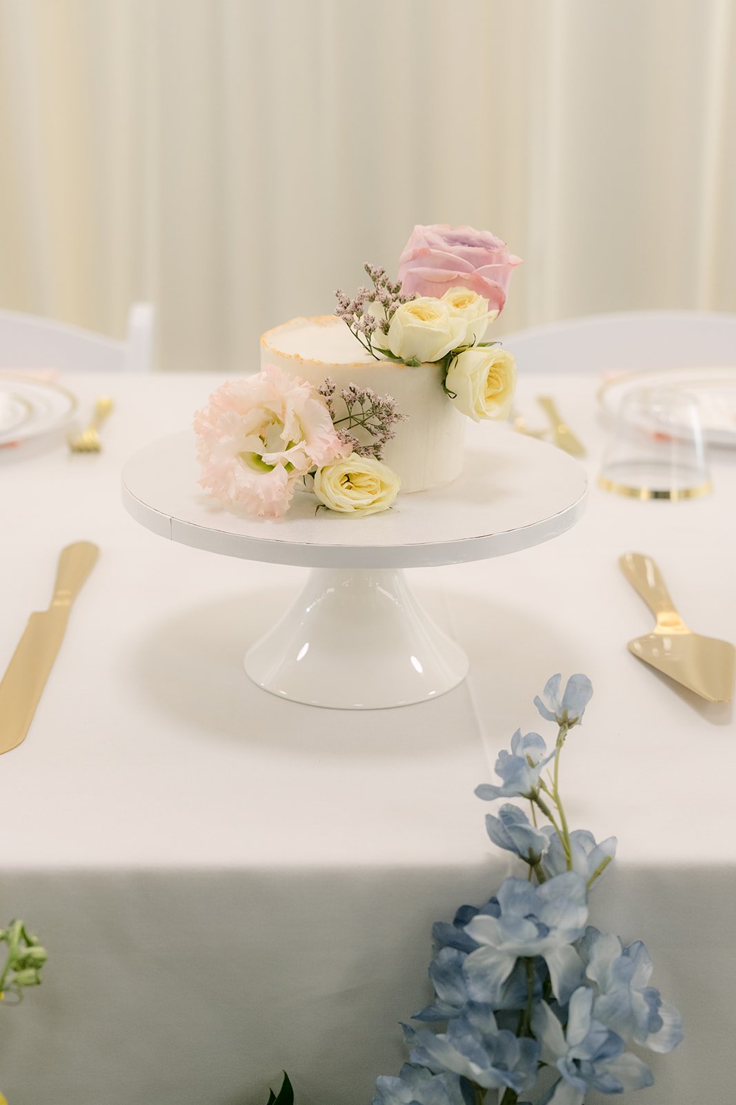 The wedding cake topped with pastel florals.