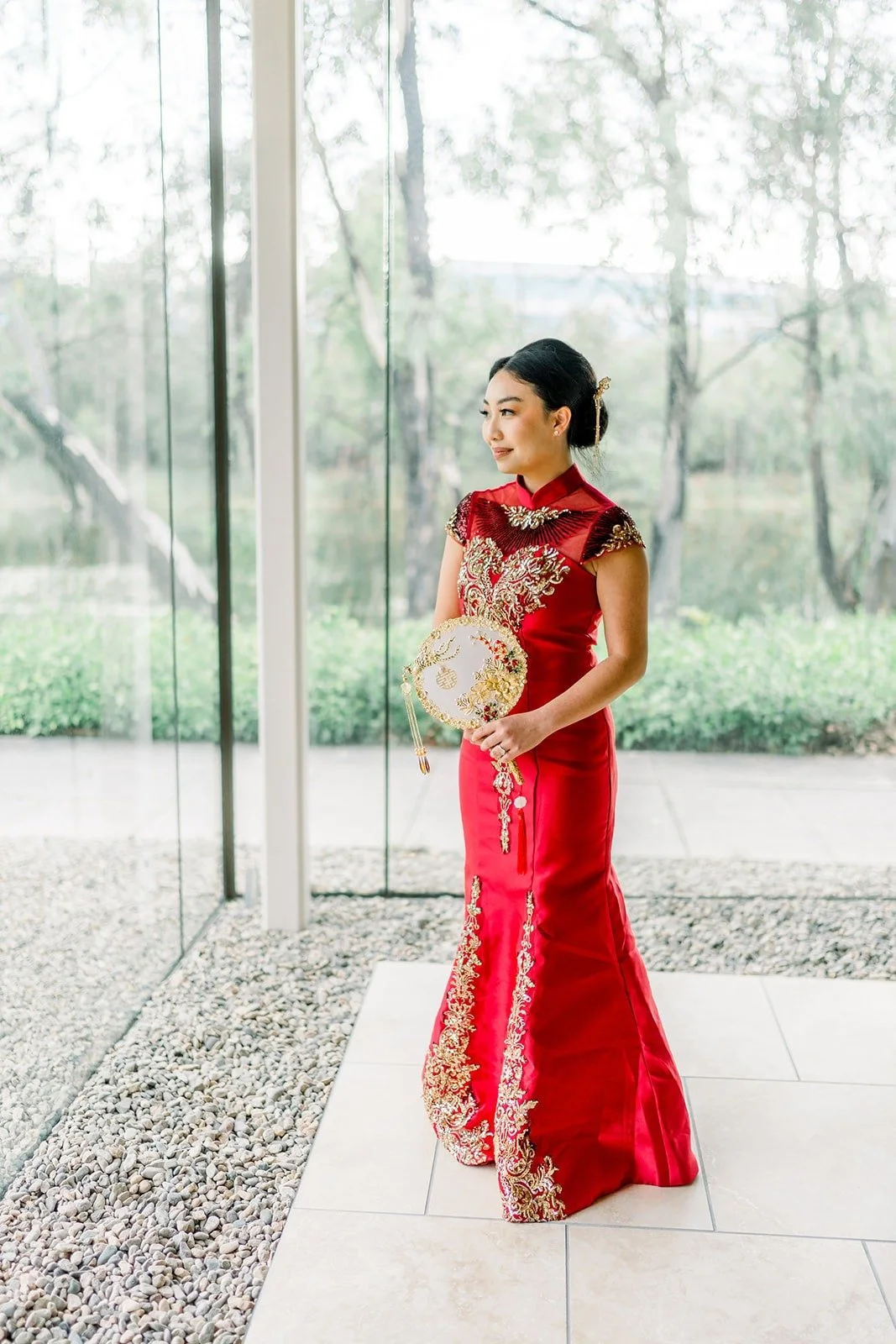 Jacinda in a red embroidered dress by the windows