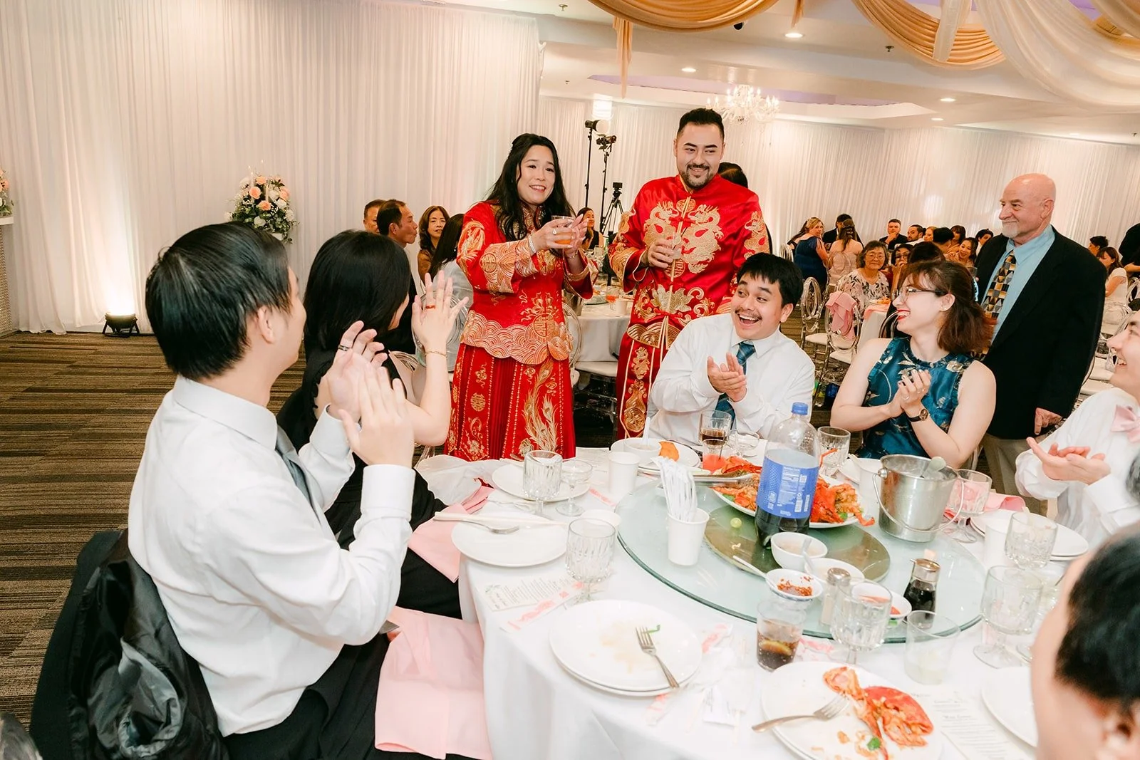 Amy and James raising a toast with a table of friends