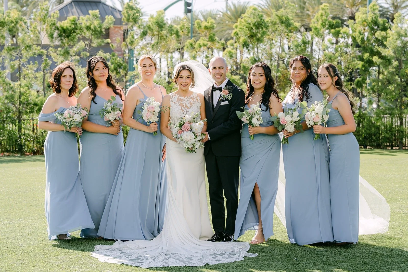 Francesca with her bridesmaids in light blue holding white bouquets