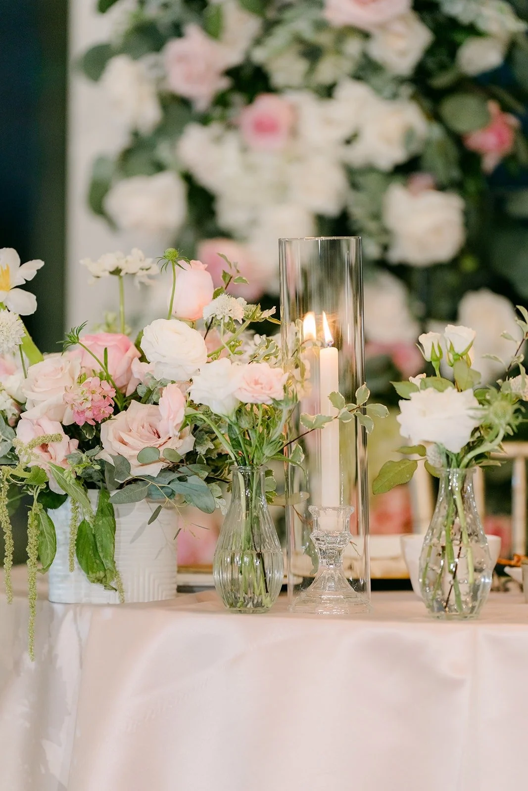 Blush and white florals in glass vases at the sweetheart table, photographed by One and Only Production