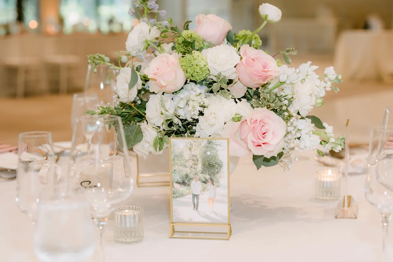 A tall blush and white centerpiece with candles on a guest table