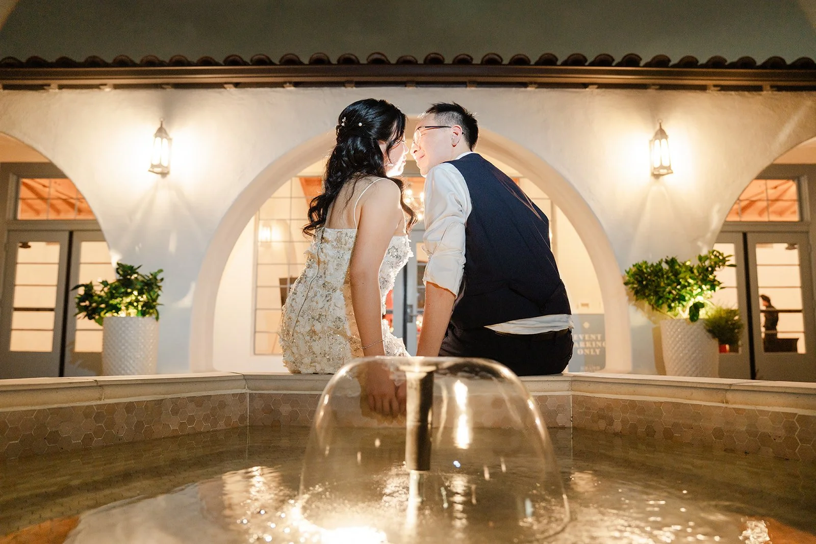 Kiss by the glowing courtyard fountain at night, photographed by One and Only Production