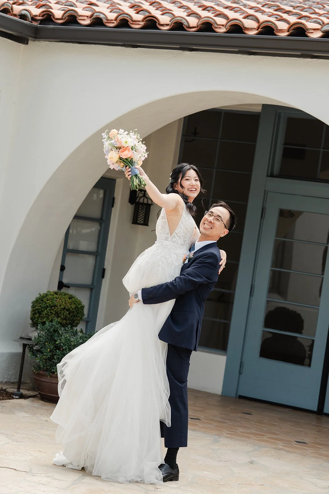 Lawrence lifting Constance as she raises her bouquet in the courtyard