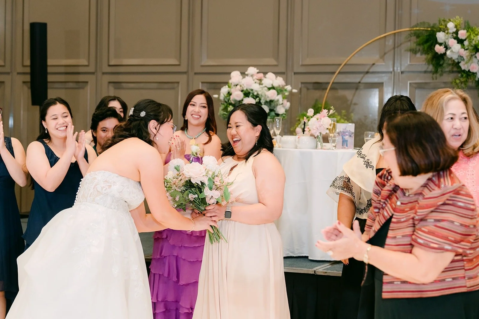 Guests reaching for the bouquet as Stella turns to look