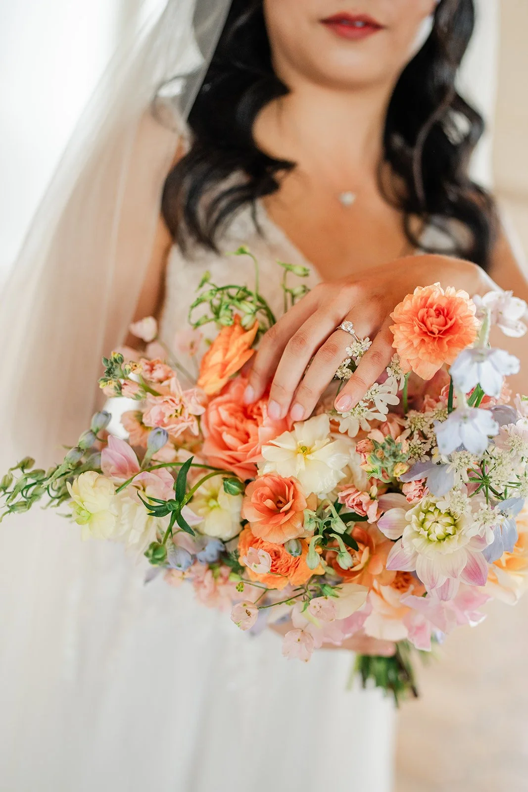 Close up of the bride's bouquet of peach dahlias, roses and soft blue blooms