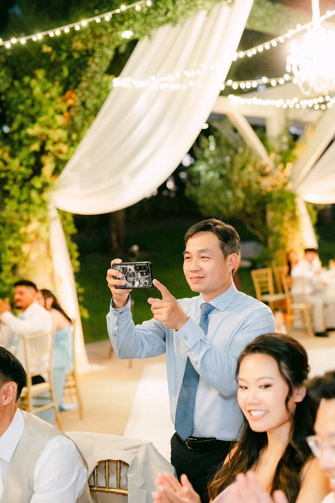 A guest filming Sandra and Kevin during the reception.